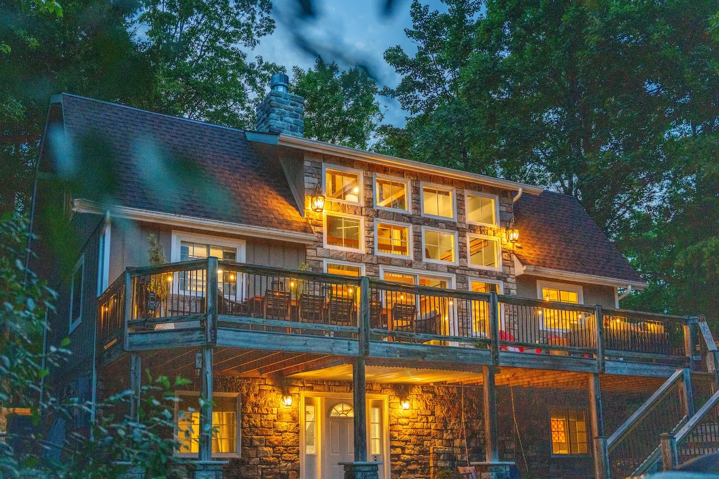 Honey Hollow: home exterior at dusk with the lit wraparound deck