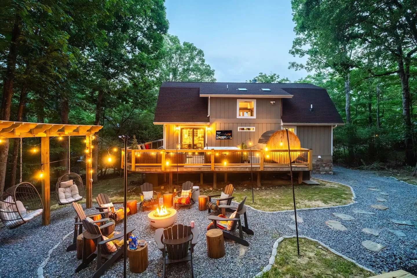 Honey Hollow: fire pit garden with Adirondack chairs and hanging swing chairs under string lights
